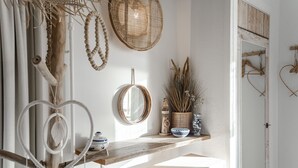 A room with a wooden shelf holding decorative items, a mirror, and a door with a rustic design. - South Beach House 3 - Studio (Zandvoort)
