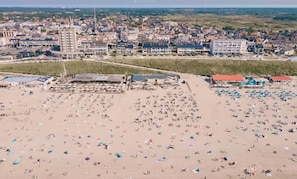 Vista aerea di una spiaggia con numerosi ombrelloni e persone.