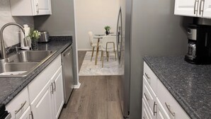 A modern kitchen with white cabinets, a stainless steel sink, a refrigerator, and a coffee maker. - Reflections - 2bdr condo in Central Raleigh (Raleigh)