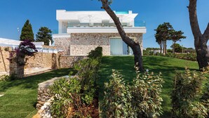 A modern house with a stone facade, a flat roof, and a large glass window. - Hotel Perla Saracena - Villette con Giardino (Torre Pali)