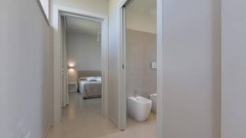 A modern hotel bathroom with a bidet, a toilet, and a shower area.