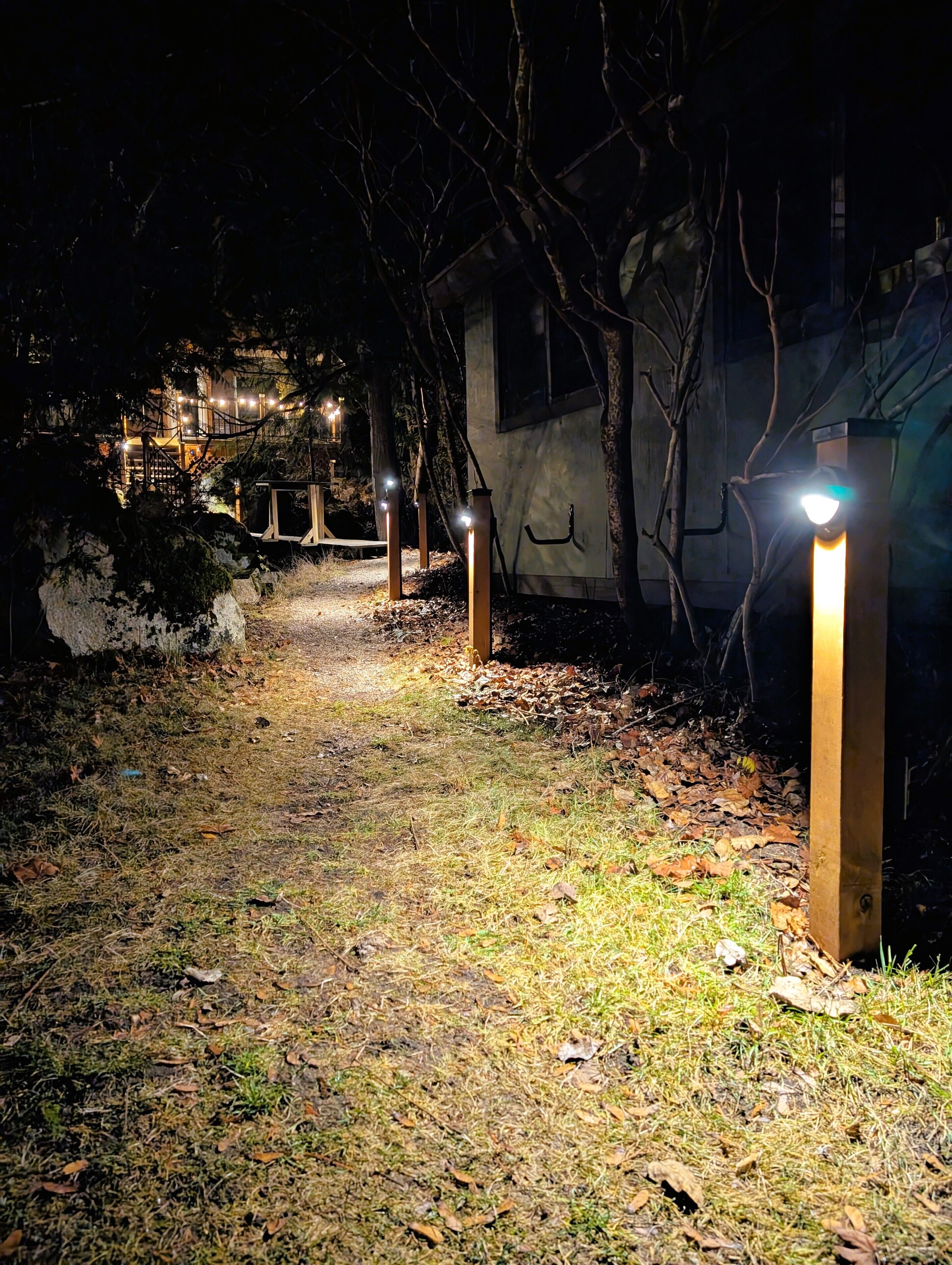 Ein beleuchteter Weg führt in der Nacht zu einem Gebäude mit rustikalem Aussehen.