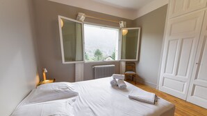 A neatly made bed with white linens, a bedside lamp, and a window with curtains. - 5 bedroom house in Annecy between town and countryside ⭐⭐⭐ (Seynod)