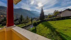 A balcony with a view of a green lawn, a red pillar, and a house in the background. - 5 bedroom house in Annecy between town and countryside ⭐⭐⭐ (Seynod)