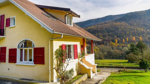 A yellow building with red shutters, a balcony, and a view of a green valley and hills. - 5 bedroom house in Annecy between town and countryside ⭐⭐⭐ (Seynod)