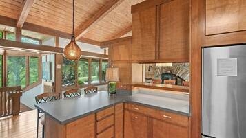 A modern kitchen with wooden cabinets, a stainless steel refrigerator, and a large island with chairs.