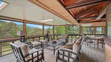 A spacious deck with outdoor furniture, large windows, and a view of the surrounding landscape.