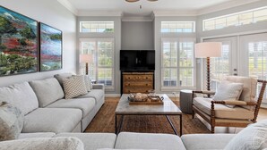 A living room with a sofa, armchair, coffee table, and a television. - Serenity Now, Sandestin's Beachside, Golf Cart, Pool (Miramar Beach)