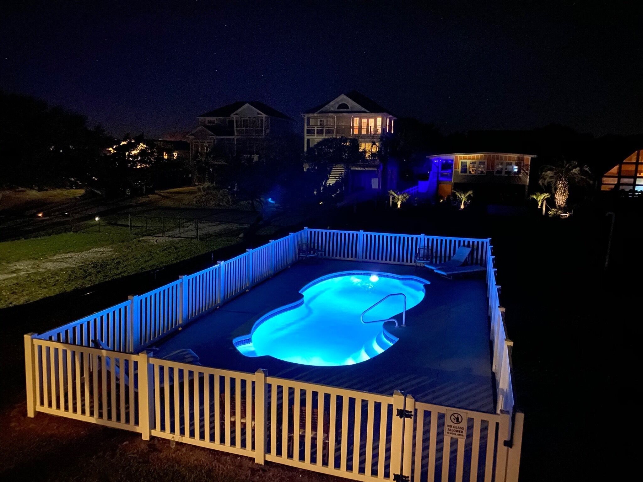 Una piscina con cubierta de madera y valla blanca.