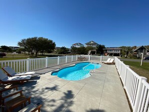 A swimming pool with a white fence, lounge chairs, and a clear blue sky. - Private Heated Pool and Hot Tub, across the street from the ocean! (Oak Island)