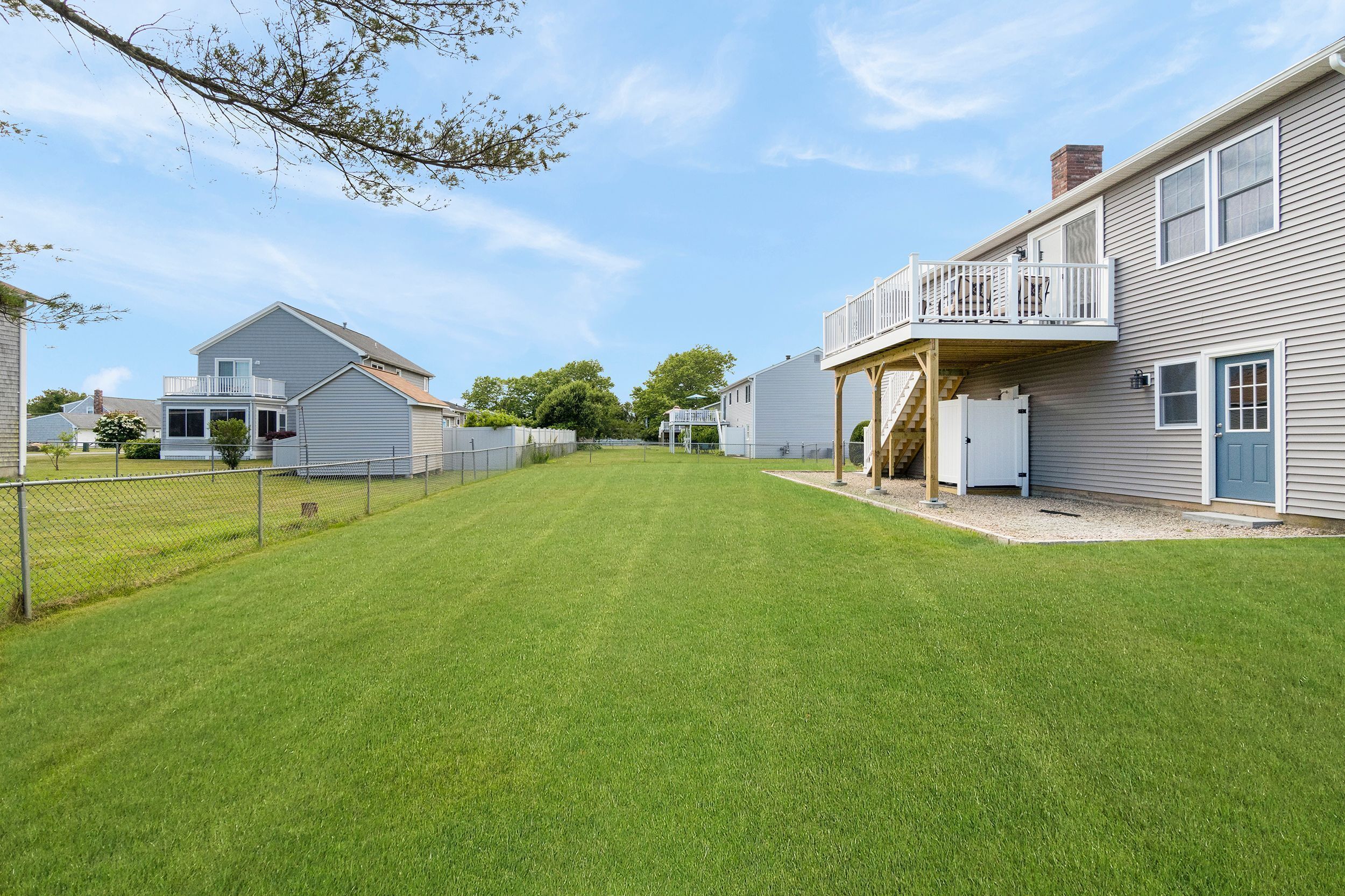 A residential property with a well-maintained lawn, a fenced yard, and a two-story house with a balcony.