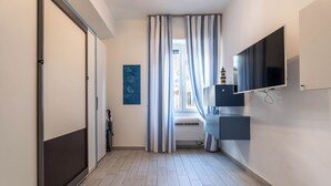 A hallway with a sliding door, a window with curtains, a mounted TV, and a wall-mounted air conditioning unit.