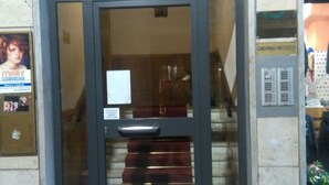 A hotel entrance with a glass door, a staircase inside, and a sign indicating the room type.