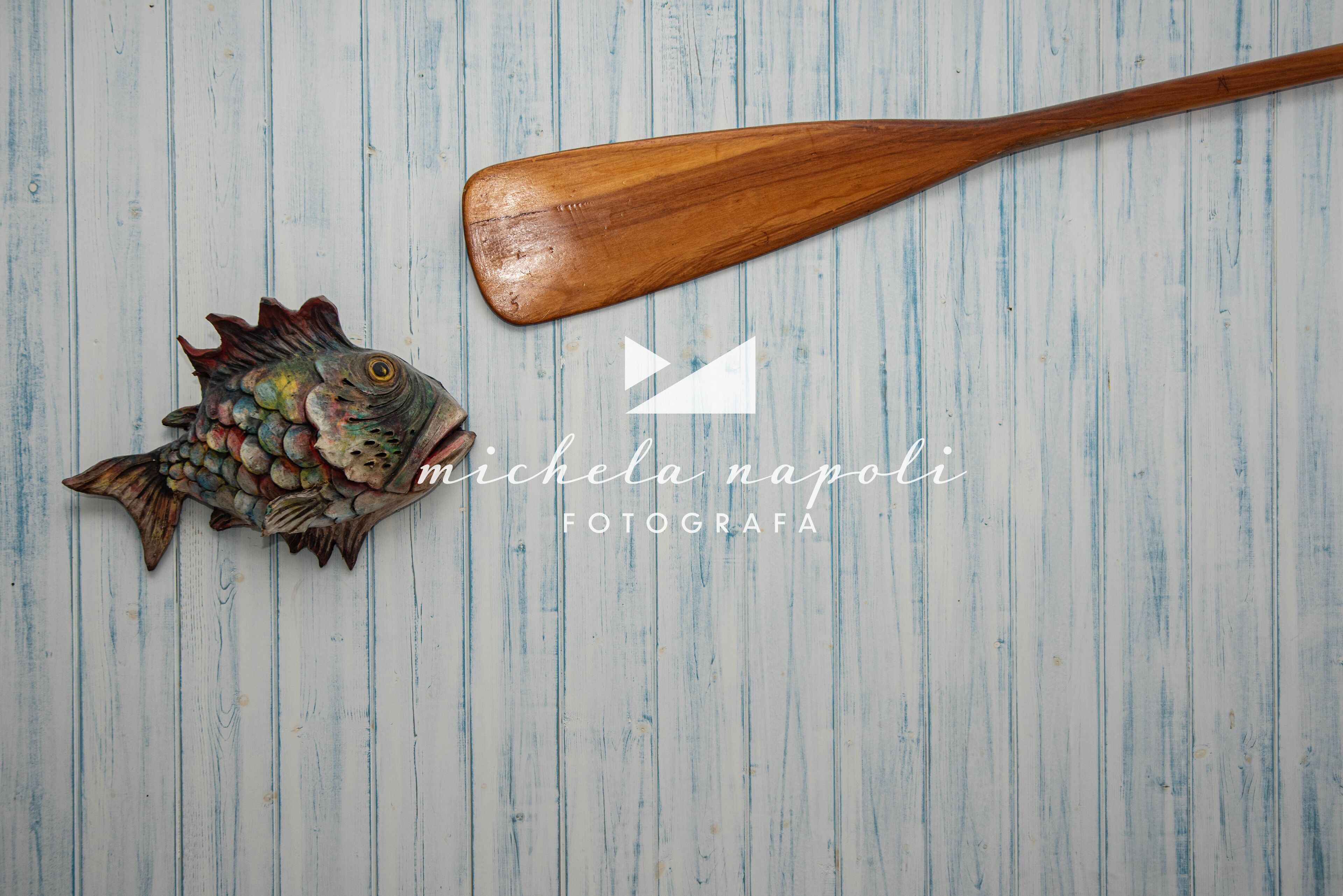 Une pagaie en bois et un poisson décoratif sur une surface en bois.