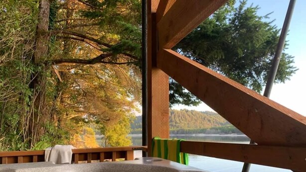 A hot tub with a view of a lake and trees.