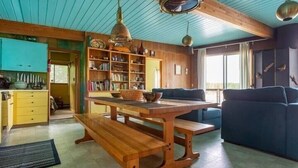 A spacious living area with a wooden dining table, blue sofa, and a bookshelf filled with books.