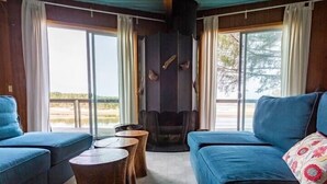 A room with a blue sofa, a small wooden table, and a large window with a view of the outdoors.