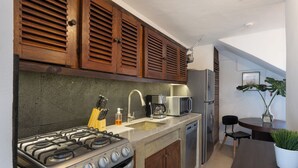 Een keuken met houten kastjes, een gasfornuis, een magnetron en een spoelbak.