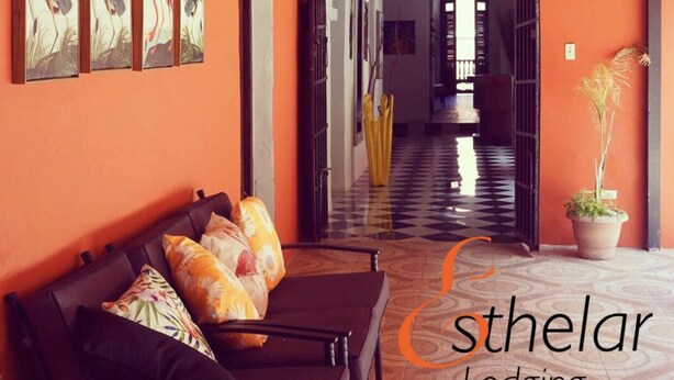 A hallway with a wooden bench and a potted plant, leading to a room with a checkered floor. - Esthelar Lodging (San Juan)