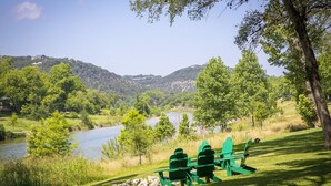 Ein Flussuferpark mit grünen Bänken und Blick auf Fluss und Hügel.
