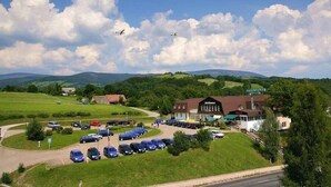A hotel with a parking lot, a restaurant, and a view of the surrounding countryside. - Hotel World of Harmony (Lánov)