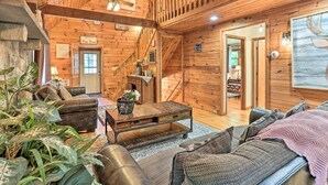 A wooden interior with a sofa, coffee table, and staircase.