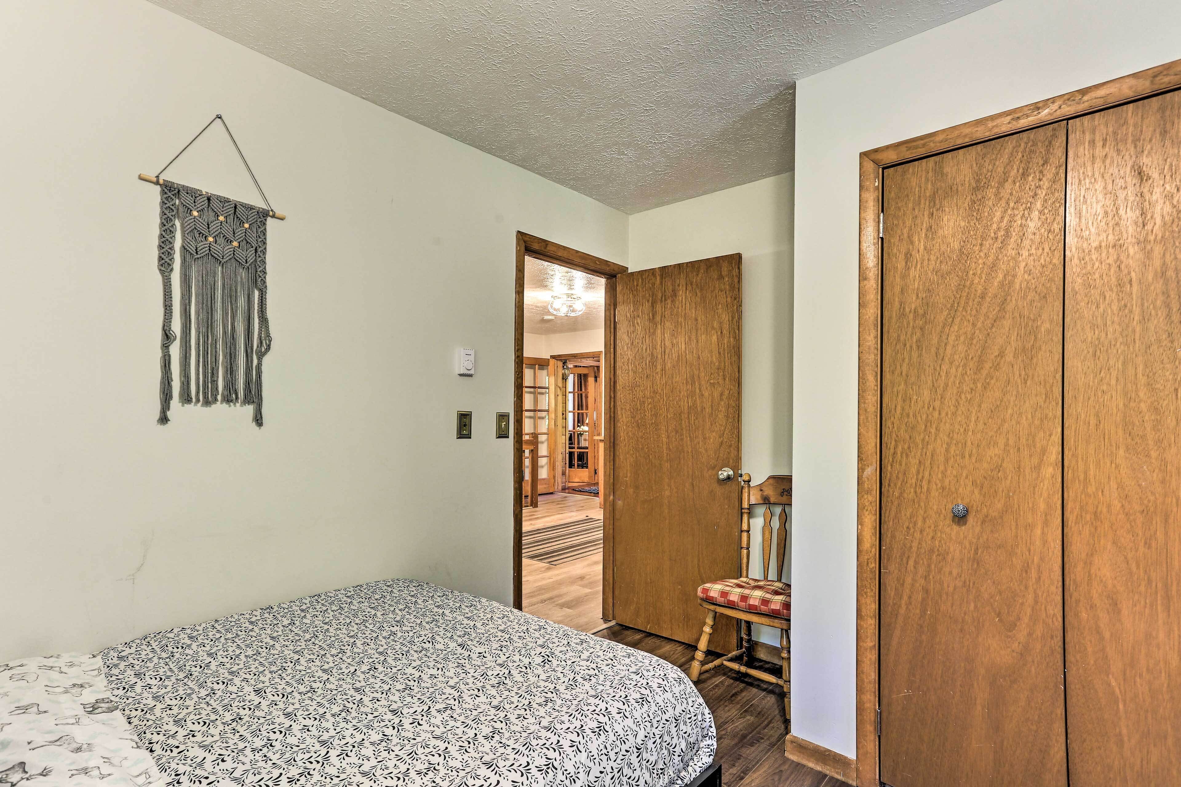 A bedroom with a bed, a wooden wardrobe, and a macrame wall hanging.