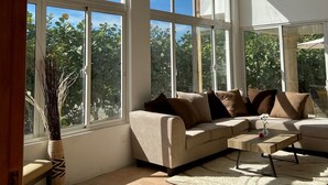 Amplia sala de estar con grandes ventanales arqueados, un sofá color beige y una mesa de centro de madera.