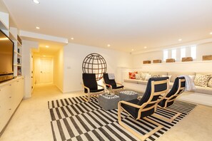 Una sala de estar moderna con un sofá, dos sillones, una mesa de centro y una alfombra estampada.