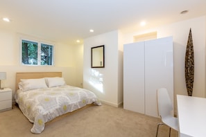 Cozy retreat with a neatly made bed, large window, and stylish storage.