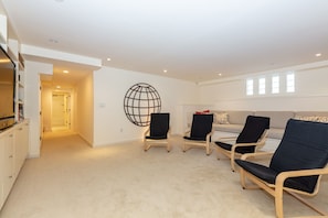 Relax in this stylish living room with a beige sofa and three lounge chairs, surrounded by a large abstract wall decoration.