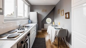Cocina compacta con estufa, lavabo y comedor con una mesa preparada para dos.