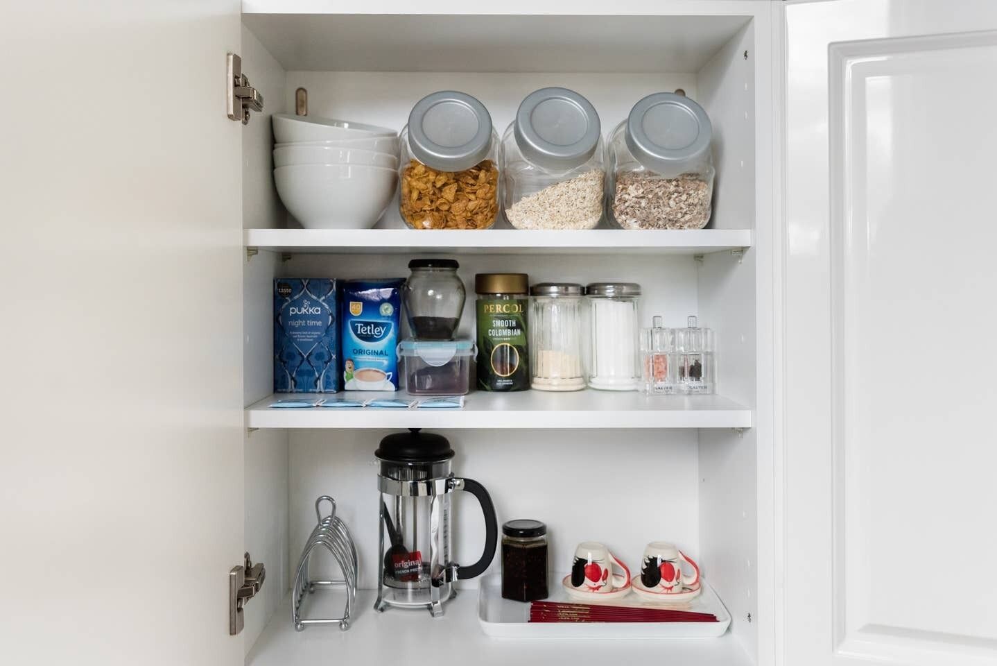 Una despensa de cocina con frascos de almacenamiento, una cafetera y utensilios de cocina.