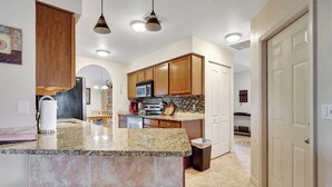 A kitchen with granite countertops, wooden cabinets, a microwave, and a sink.