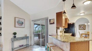 A modern kitchen with a granite countertop, wooden cabinets, and pendant lighting.