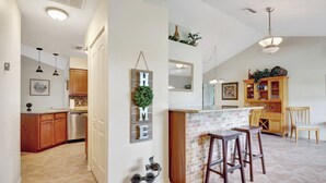 A spacious kitchen with wooden cabinets, a brick island, and pendant lighting.