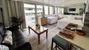 Ein modernes Hotelzimmer mit einem großen Bett, einer Couch, einem Esstisch und einem Balkon mit Blick.