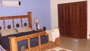 Ein Schlafzimmer mit einem hölzernen Bett, einem Nachttisch, einer Lampe, einem Heizgerät und einem Kleiderschrank.