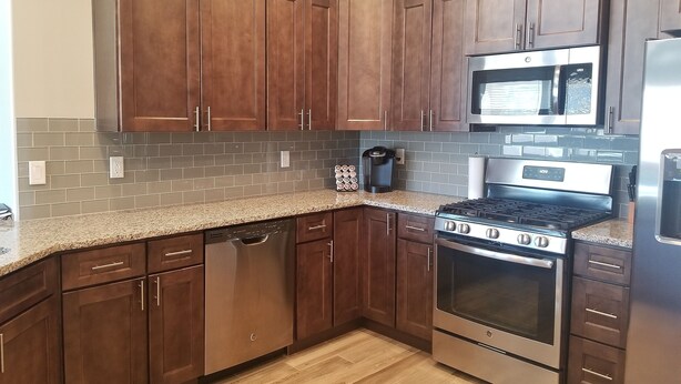 A kitchen with wooden cabinets, a granite countertop, a stainless steel stove, and a microwave. - Beautiful Home near Zions with PRIVATE POOL, GAZEBO and GARAGE (La Verkin)
