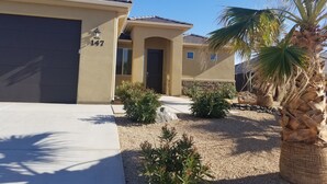 A residential house with a beige exterior, a dark garage door, and a number '147' on the wall. - Beautiful Home near Zions with PRIVATE POOL, GAZEBO and GARAGE (La Verkin)