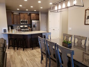 Enjoy meals in the kitchen with a central island, stainless steel appliances, and a dining area with a glass table.
