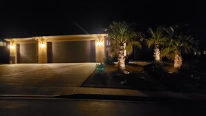 A well-lit garage with a number 147 sign, a paved driveway, and two palm trees with lights. - Beautiful Home near Zions with PRIVATE POOL, GAZEBO and GARAGE (La Verkin)