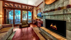 Una sala de estar con chimenea, televisión y vista al océano a través de grandes puertas corredizas de vidrio.