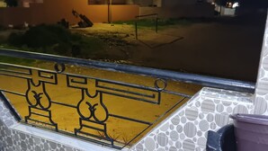 Parveke, jossa on kuvioitu lattia, metallikaide ja näkymä yöllä valaistuun kaduun.