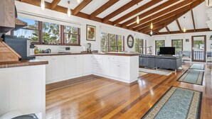 A spacious kitchen with wooden beams, white cabinetry, and a large island.
