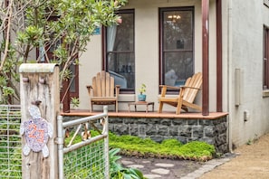 A porch with two wooden chairs, a small table, and a potted plant.