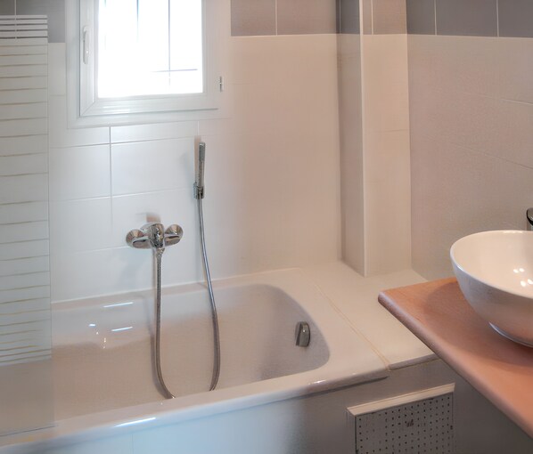 Een badkamer met een bad, douche en wastafel.