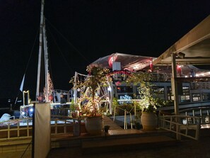 A waterfront restaurant with outdoor seating, potted plants, and a covered area with string lights. - Charming sunset,with Panoramic Nile view and pyramid view. (Cairo)