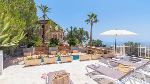 Une terrasse sur le toit avec des chaises longues, une piscine et une vue sur la mer.