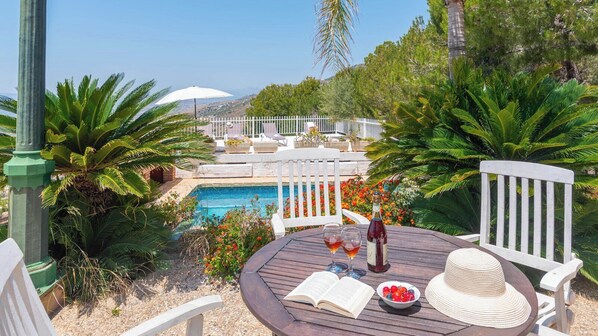 Relax by the serene pool surrounded by lush greenery and comfortable lounge seating.